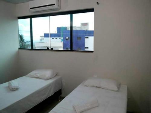 two beds in a room with a window at Hotel Reobot in Garanhuns