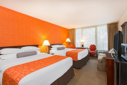 a hotel room with two beds and a flat screen tv at Howard Johnson by Wyndham Williamsburg in Williamsburg