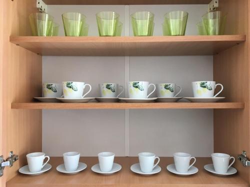 a group of cups and saucers on a shelf at Apartment Smestaj B in Novi Pazar