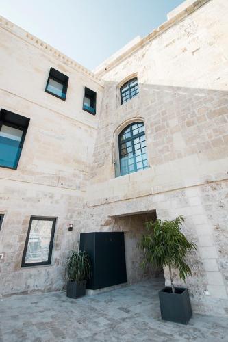 a stone building with two potted plants in front of it at Cugo Gran Macina Malta in Senglea