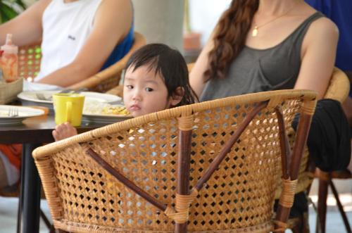 a young child sitting in a chair at a table at Lamphu House Chiang Mai in Chiang Mai