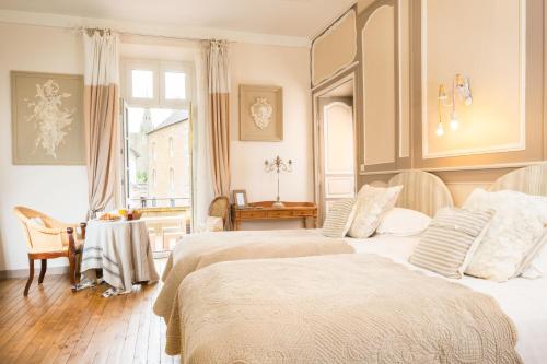 a bedroom with two beds and a table and a window at La Demeure in Guingamp
