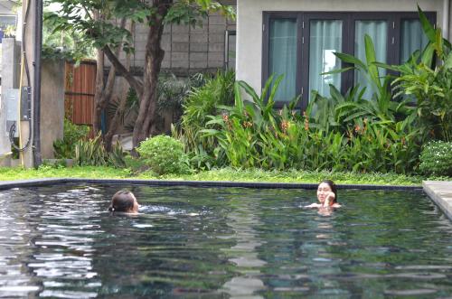 two people swimming in a swimming pool at Lamphu House Chiang Mai in Chiang Mai