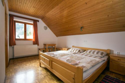 - une chambre avec un grand lit et un plafond en bois dans l'établissement Turistična kmetija Perk, à Solčava