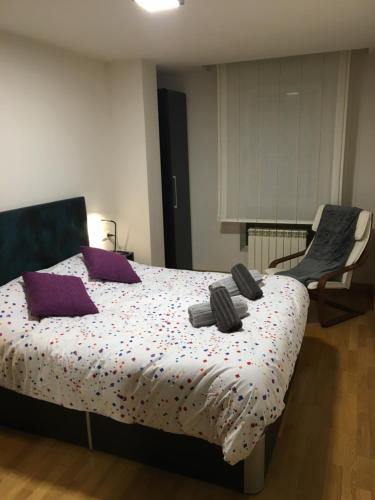 Un dormitorio con una cama con almohadas moradas y una silla en SkyLinePamplona en Pamplona