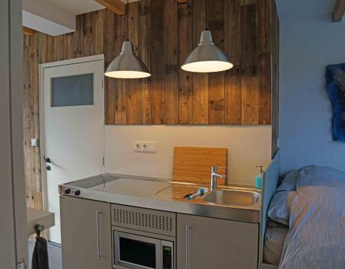 eine Küche mit Spüle und zwei Lampen darüber in der Unterkunft Studio Zilt in Vlissingen