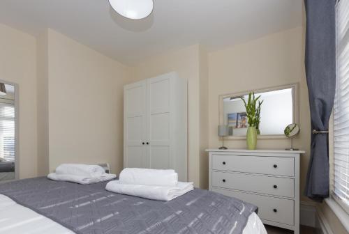 - une chambre avec un lit, une commode et un miroir dans l'établissement Prince Apartments, à Fareham