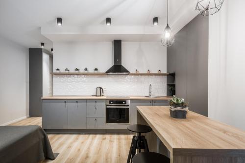 a kitchen with white cabinets and a wooden counter top at Uptown studio apartment in Vilnius