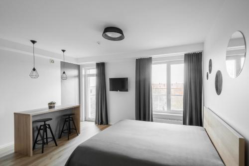 1 dormitorio con cama, escritorio y ventana en Uptown studio apartment en Vilna