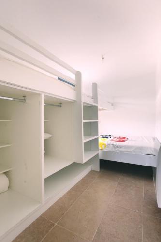 - une chambre blanche avec des étagères blanches et un lit dans l'établissement Le 27, à Malaucène