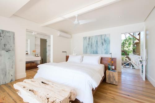 a white bedroom with a large bed and a table at Ibagari Boutique Hotel in Roatan