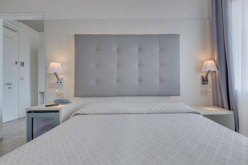 a bedroom with a large white bed with two lamps at Hotel Garni' Serena in Caorle