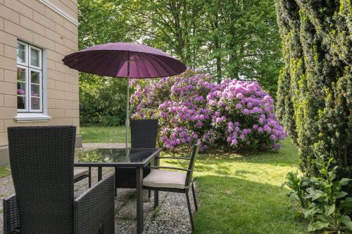 a table and chairs with an umbrella and flowers at Haus Flora in Keitum