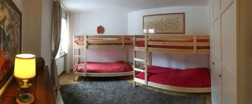 a bedroom with three bunk beds with red sheets at Un nido in centro in Madesimo