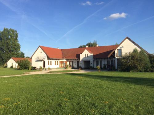 a large white house with a red roof at KARÁM Vendégház és Lakásétterem in Nagybajcs