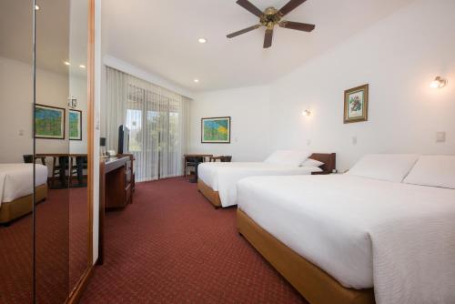 a hotel room with two beds and a television at Hotel Bougainvillea San José in Santo Domingo