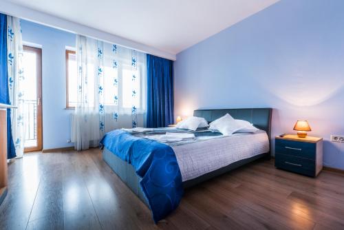 a bedroom with a bed with blue walls and wooden floors at Pensiunea Christiana in Arad