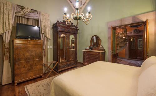 a bedroom with a bed and a dresser and a television at Hotel Museo Palacio de San Agustin in San Luis Potosí