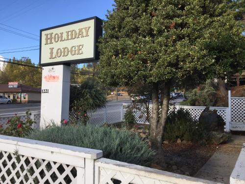 a sign for a holiday lodge next to a tree at Holiday Lodge in Grass Valley