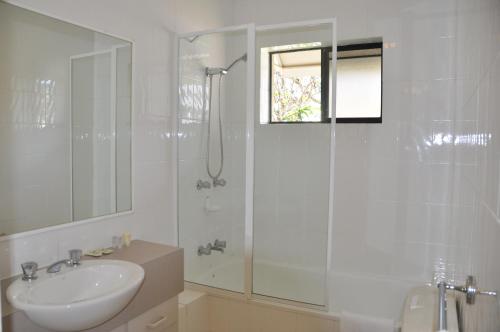 a white bathroom with a sink and a shower at Spring Hill Gardens Apartments in Brisbane