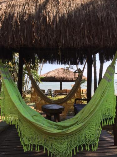a hammock on a beach with a thatch roof at Pousada D'Aconchego Nova Brasilia in Ilha do Mel