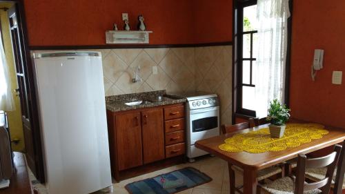 a kitchen with a table and a refrigerator at Pousada Santa Genoveva campeche in Florianópolis