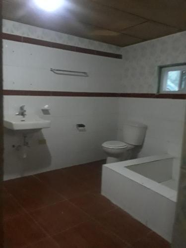 a bathroom with a toilet and a sink and a tub at Pablo Guess House in Cap-Haïtien
