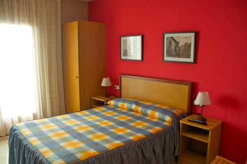 サント・パウ・デ・セゴリアスにあるアビタシオンス オウロラの赤い壁のベッドルーム1室(ベッド1台付)