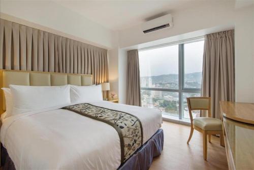 a hotel room with a bed and a desk and a window at Quest Serviced Residences in Cebu City