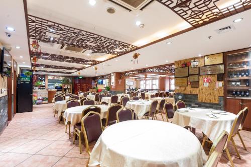 un comedor con mesas y sillas blancas en Guangzhou Compass Hotel, en Guangzhou