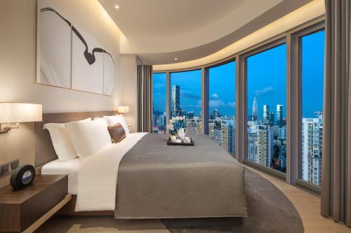 a bedroom with a large bed with a view of a city at Ascott Raffles City Shenzhen in Shenzhen