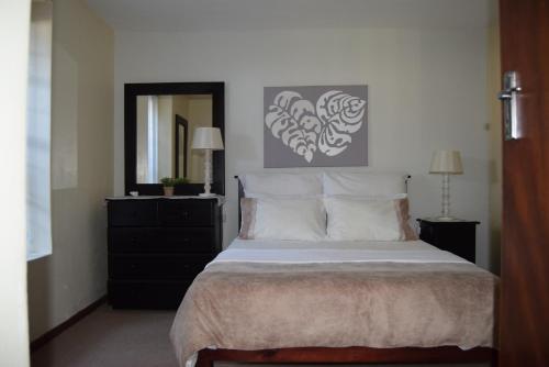 een slaapkamer met een groot bed en een spiegel bij Hoog 109 High accommodation in Mosselbaai