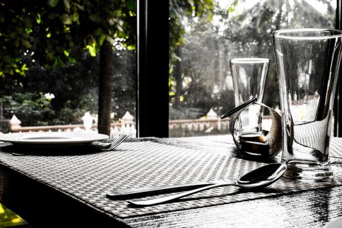 a table with utensils and a plate and a glass at The Ivy Anjuna in Anjuna