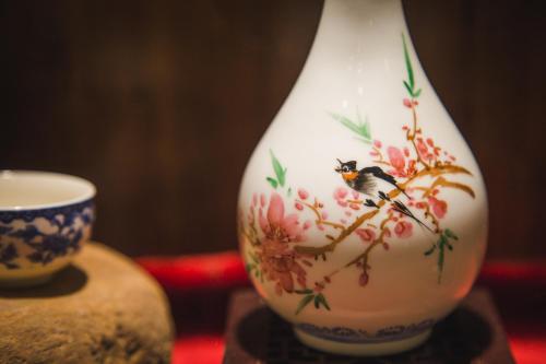 a vase with a bird painted on it next to a cup at Leisure Courtyard Hotel Yangshuo in Yangshuo