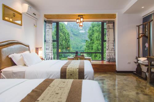 two beds in a room with a large window at Leisure Courtyard Hotel Yangshuo in Yangshuo