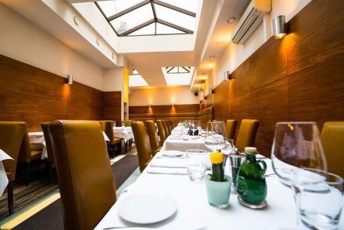 a long table in a restaurant with white tables and chairs at Hotel Marc Aurel - Vienna City Center in Vienna