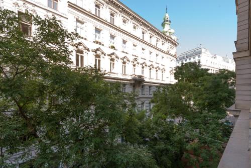 a white building with a green tree in front of it at Hotel Marc Aurel - Vienna City Center in Vienna