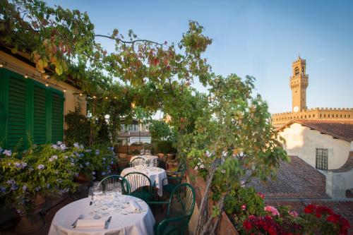 a patio with tables and chairs and a clock tower at Hotel Hermitage in Florence