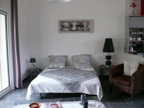 a bedroom with a bed and a chair at Les Karakis, piscine au sel, jardin 5000m2 in Les Arcs sur Argens