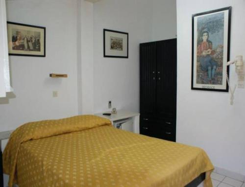 a bedroom with a bed with a yellow bedspread at Andrea Pension in Hydra