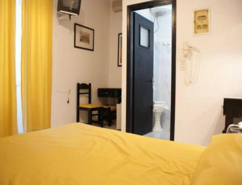a bedroom with a yellow bed and a mirror at Andrea Pension in Hydra