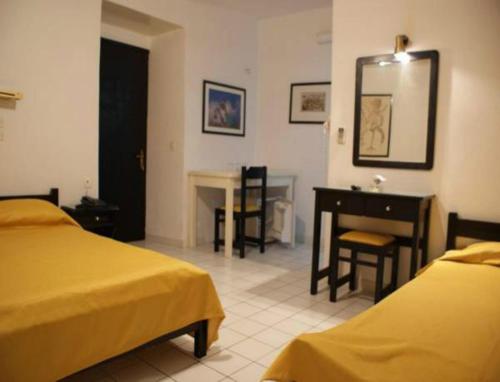 a bedroom with two beds and a desk and a table at Andrea Pension in Hydra