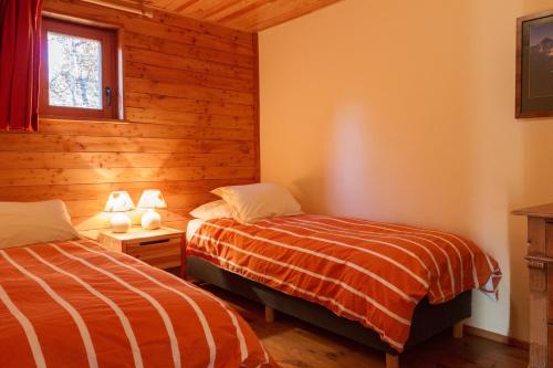 two beds in a room with wooden walls at Chalet Il fera beau demain in Villard-Reculas