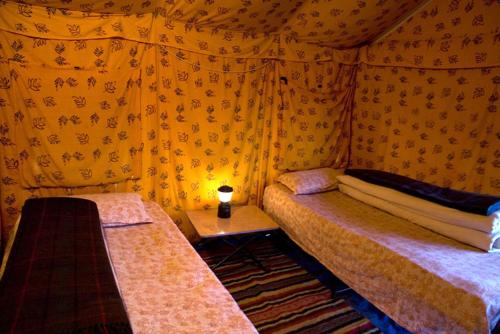 - une chambre avec deux lits et une table avec une lampe dans l'établissement Mulkila Adventure Camp, à Leh