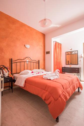 a bedroom with a large bed with orange walls at Villa Voula in Perissa
