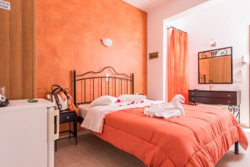 - une chambre dotée d'un lit avec un mur orange dans l'établissement Villa Voula, à Perissa