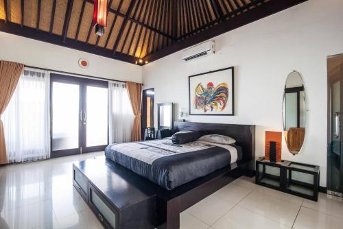 a bedroom with a large bed in a room with windows at Villa L'Orange Bali in Keramas