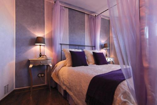1 dormitorio con 1 cama grande y cortinas moradas en Hotel Rural La Tenada en Carcedo de Burgos