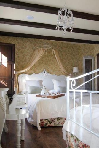 a bedroom with a white bed and a chandelier at Hotel Rural La Tenada in Carcedo de Burgos
