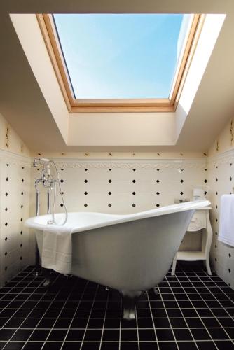 a large white bath tub in a bathroom with a skylight at Hotel Rural La Tenada in Carcedo de Burgos